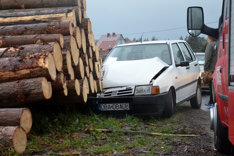 Osobowy Fiat wjechał w składowane przy drodze bale drewna. - Zdjęcie główne